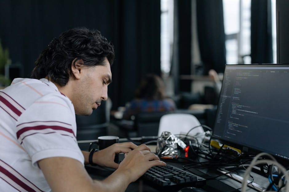 A coder intensely typing at a workstation in a contemporary office setup